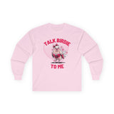 Women's Valentine's Day shirt featuring a humorous and flirty design. The pink long-sleeve t-shirt showcases a cartoon-style bird dressed in red lace lingerie with a playful expression, complete with a red bow on its head. The background includes a large pink heart with floating smaller hearts, adding to the romantic theme. Bold pink text above and below the bird reads "TALK BIRDIE TO ME," making this a fun Valentine's shirt perfect for bird lovers and those with a cheeky sense of humor.