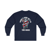 A navy blue long sleeve t-shirt featuring a cool Santa Claus wearing sunglasses and dancing. Above him, the bold white text reads "THERE'S SOME HO'S IN," and below, "THIS HOUSE" is written in large white capital letters. 